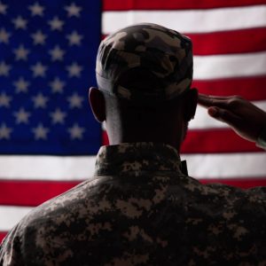 Rear View Of Military Man Saluting Us Flag