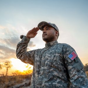 Us Army veteran honors Veterans Day. Man soldier adjusts the US military patch before duty. A US soldier with an American flag patch on his uniform prayers for Memorial Day. Independence Day