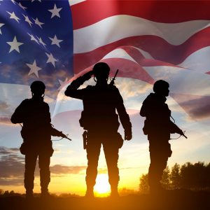 Silhouettes of a soldiers with USA flag against the sunset. Veterans Day, Memorial Day concept