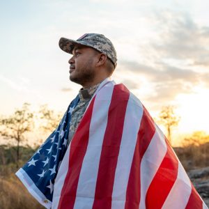 Hand Waving the Flag of the United States of America in memorial day . Us soldier holding American flag celebrating.US Army soldier celebrates holding USA flag celebrating Independence USA day